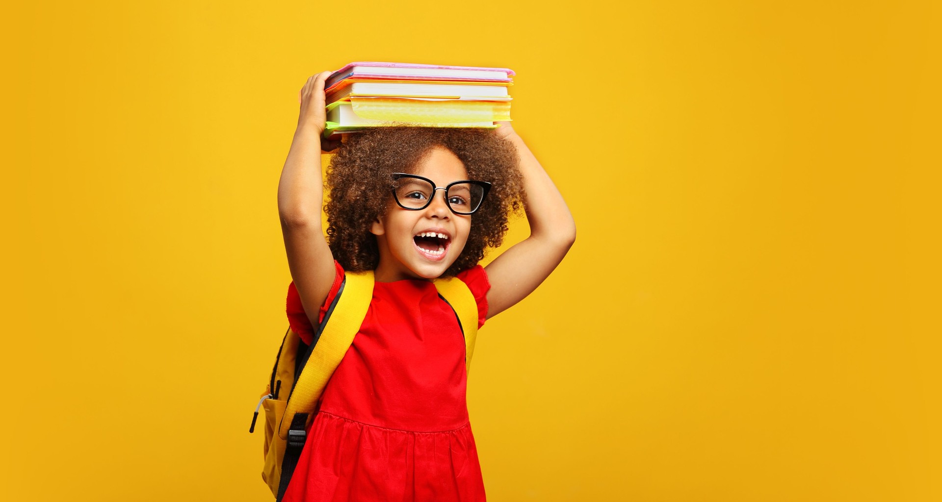 funny smiling Black child school girl with glasses hold books on her head