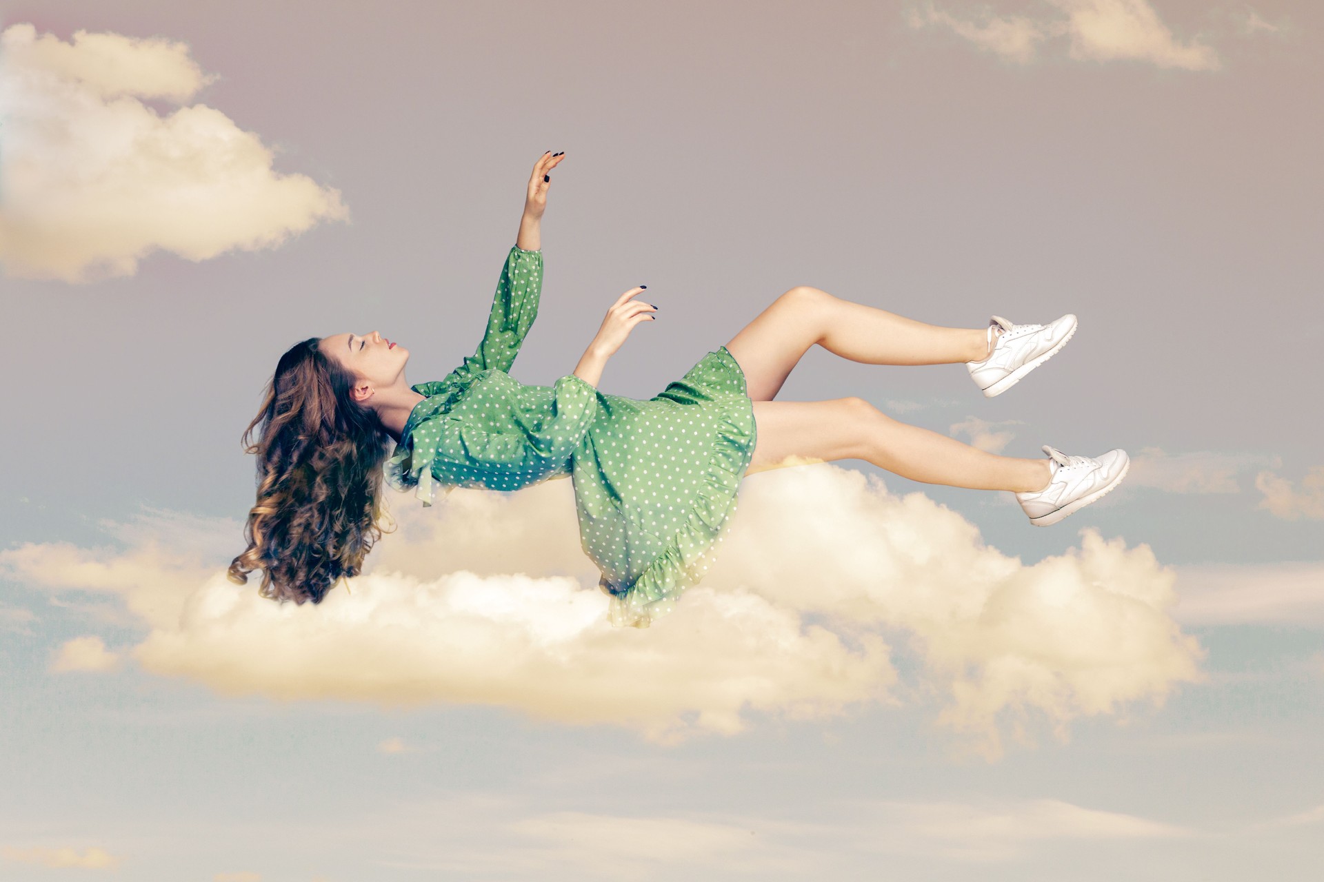 Young woman in dress flying and sleep in the sky.